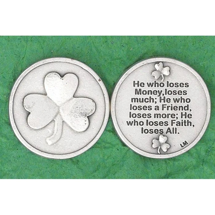 Two round silver-toned coins or medallions shown side by side on a textured green background. The left coin features a raised shamrock design, and the right coin has a shamrock at the bottom and printed text about losing money, friend, and faith.
